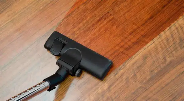 Cabezal de aspiradora limpiando suelo laminado. El suelo laminado se ve brillante y limpio tras pasar la aspiradora.