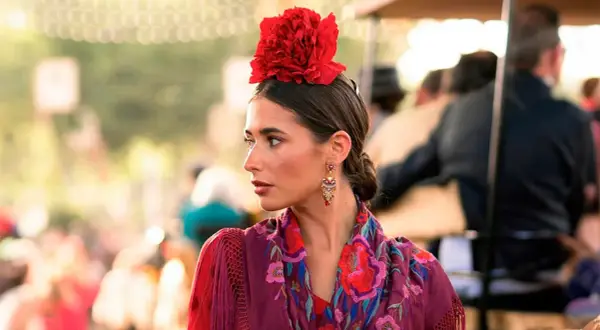 Mujer con flor flamenca en su pelo corto, pendientes llamativos y mantón bordado.