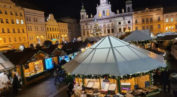 Festlicher budweis weihnachtsmarkt mit beleuchteten Buden, einem Weihnachtsbaum und historischen Gebäuden im Hintergrund.