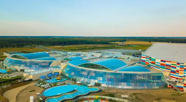 Nowoczesny kompleks z basenami i zjeżdżalniami, największy park wodny w Polsce, otoczony zielenią.