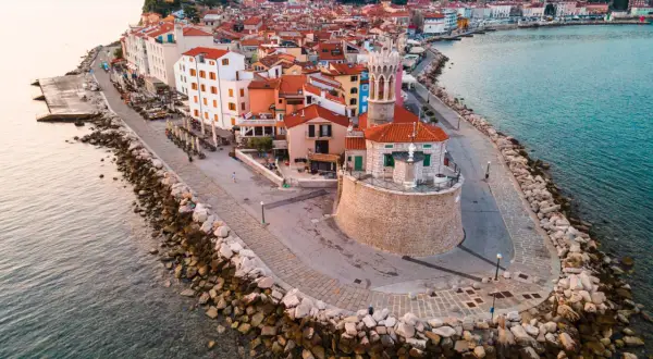 Piran plaża: malownicze miasteczko na półwyspie, z kolorowymi domami, kamienną promenadą i wieżą kościelną górującą nad Adriatykiem.