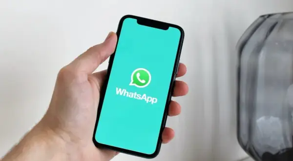 Dłoń trzyma smartfon z włączoną aplikacją WhatsApp. Widzisz, jak działa WhatsApp w telefonie, dzięki czemu możesz łatwo rozmawiać z bliskimi.