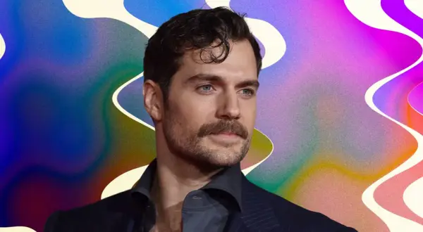 Un homme au regard intense, sa moustache parfaitement taillée, sur un fond abstrait aux couleurs vives.