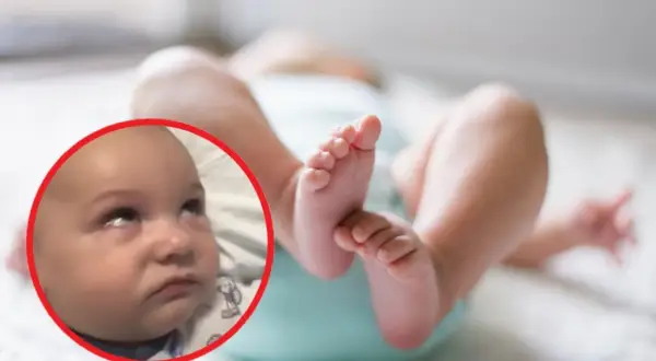 Dziecko z wyrazem twarzy sugerującym niepokój. W tle jego nóżki. Obraz może ilustrować padaczka objawy u niemowląt.