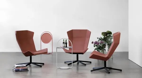 Tre moderna fåtöljer från Johanson Design i terrakottafärgad klädsel, placerade i ett stilrent rum med en sidobänk och blommor.