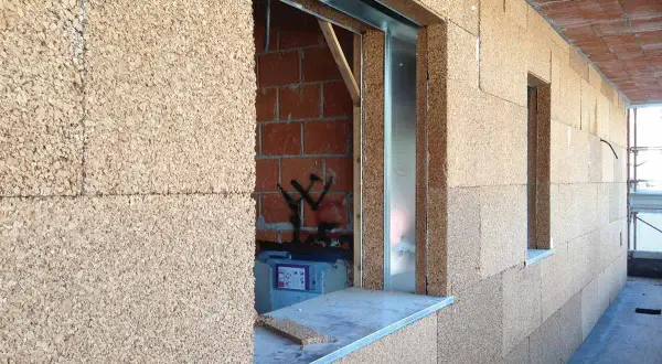 Blocchi di sughero, il miglior isolante termico naturale, rivestono le pareti di un edificio in costruzione, con aperture per finestre.