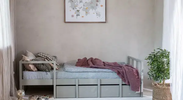 Przytulne łóżko dla nastolatków z szufladami, ozdobione mapą świata na ścianie. Idealne miejsce na marzenia o podróżach.