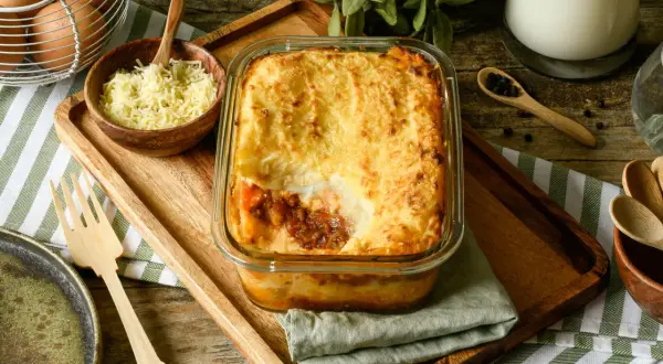Un delicioso pastel de carne gratinado, listo para servir. Acompañado de queso rallado, huevos y especias.