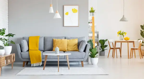 Graue wandfarben im Wohnzimmer harmonieren perfekt mit gelben Akzenten auf dem Sofa und dem Essbereich.