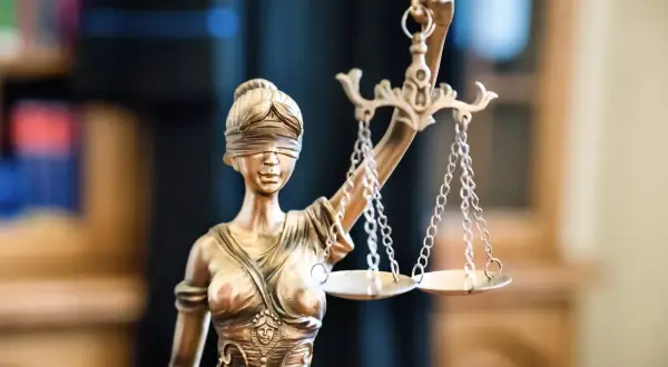 Figurka Temidy z wagą symbolizuje sprawiedliwość, kluczową przy zawieraniu umowy rezerwacji mieszkania.