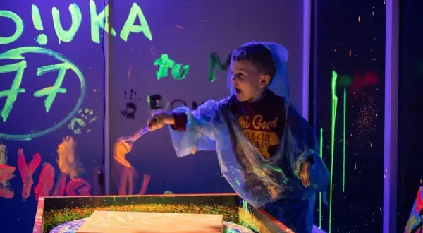 Chłopiec maluje farbami fluorescencyjnymi w ciemni. Świetne atrakcje dla dzieci w Szczecinie!