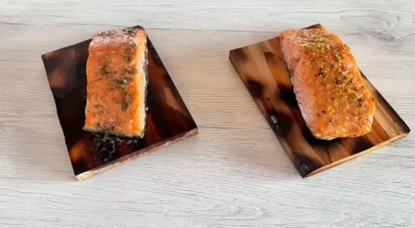 Due tranci di salmone, uno condito con aneto e l'altro con scorza di limone, pronti per essere gustati.
