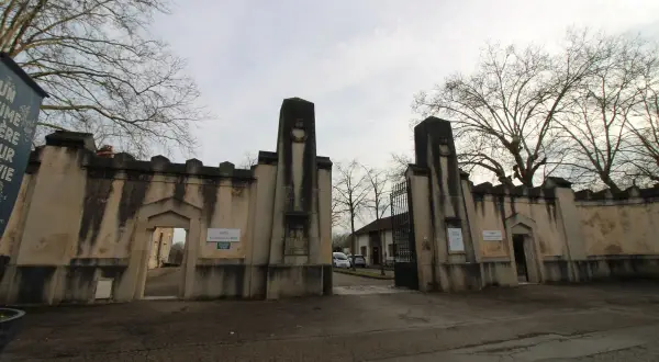 Entrée imposante du cimetière du Sud à Nancy, avec ses piliers de pierre patinés par le temps et ses grilles ouvragées.