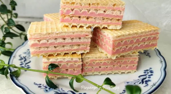 Słodkie wafle z mlekiem w proszku, przełożone różowym kremem, ułożone na talerzyku z niebieskimi wzorami.