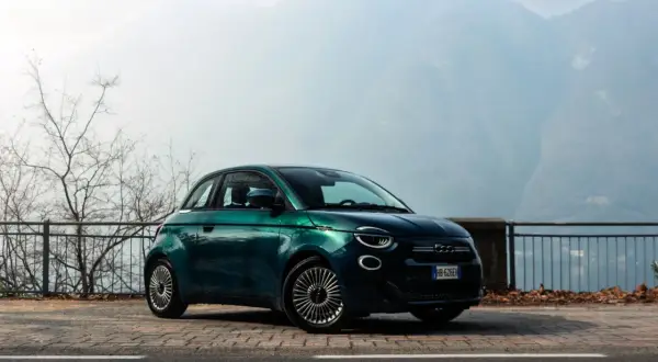 Zielony Fiat 500 na tle górskich krajobrazów. Wiele osób chwali ten model, a jego opinie są bardzo pozytywne.