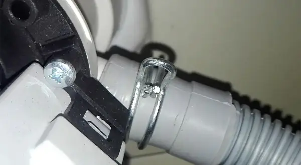 Dettaglio del tubo di scarico della lavatrice, fissato con fascetta metallica. Utile per capire come pulire il tubo di scarico della lavatrice.