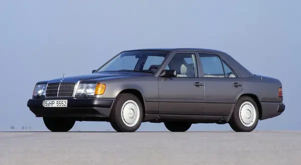 Szary Mercedes-Benz W124, symbol najbardziej niezawodnych samochodów, stoi na pustej drodze.