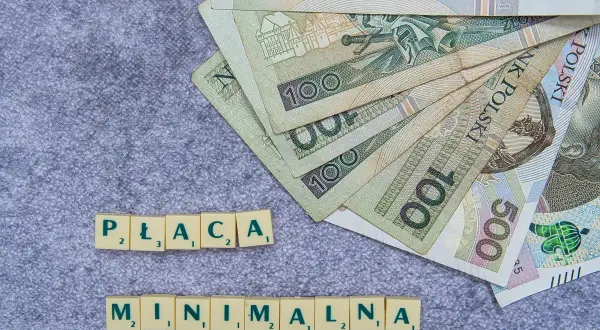 Płaca minimalna w Polsce to temat dyskusji. Na zdjęciu polskie banknoty i litery tworzące hasło.