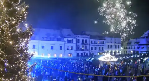 Świąteczna iluminacja i fajerwerki nad rynkiem w Kazimierzu Dolnym. Tłumy ludzi świętują nadchodzące wydarzenia.