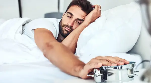 Man struggling to wake up, embodying the dysania meaning of difficulty getting out of bed.