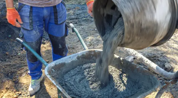 Robotnik wylewa beton z betoniarki do taczki. Czy ktory cement lepszy 32 5 czy 42 5?