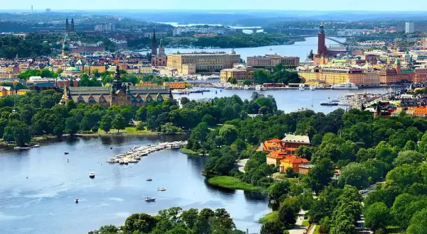 Widok na miasto z wodą i zielenią. W oddali widać budynki, a na pierwszym planie rzekę z łodziami. To piękny krajobraz, jakby z lotniska Nyo.