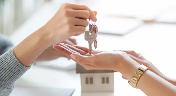 Un asesor compra vivienda entrega las llaves de una casa modelo a un cliente.