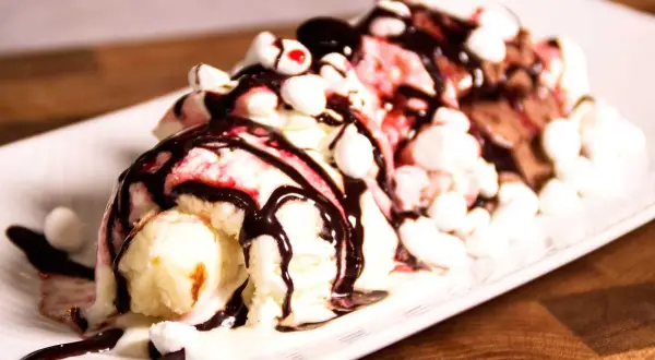 En läcker banana split med tre kulor glass, chokladsås, marshmallows och körsbär.