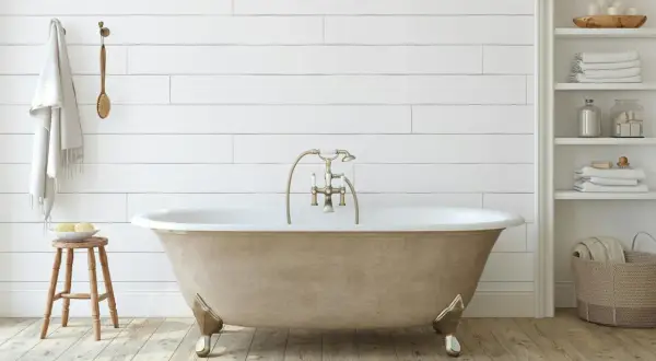 Bagno moderno con vasca da bagno color sabbia, rubinetteria dorata e asciugamani bianchi. Un progetto di verniciare vasca da bagno per un look rinnovato.