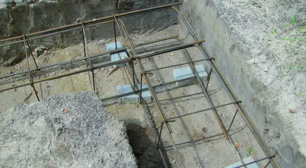 Zbrojenie wieńca w narożu fundamentu, gotowe do zalania betonem. Stalowe pręty tworzą solidną konstrukcję.