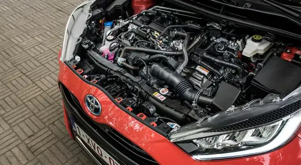 Silnik Toyoty Yaris 1.0. Widok komory silnika z widocznym zbiorniczkiem płynu chłodniczego i innymi elementami.