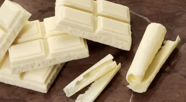 Barras de chocolate blanco, algunas enteras y otras desmenuzadas, demuestran que el chocolate blanco es chocolate.