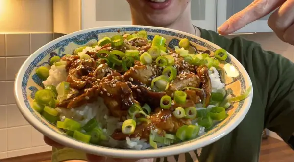 Leckeres Hähnchen Teriyaki Rezept: saftiges Hähnchen in Teriyaki-Sauce auf Reis, garniert mit Frühlingszwiebeln und Sesam.