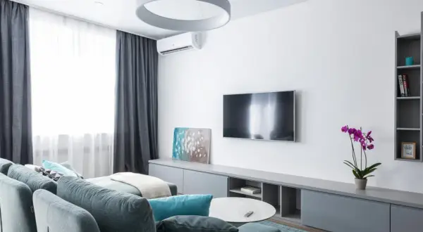 Nowoczesny salon z kanapą, telewizorem i klimatyzacją. Zastanawiasz się, ile kosztuje montaż klimatyzacji?