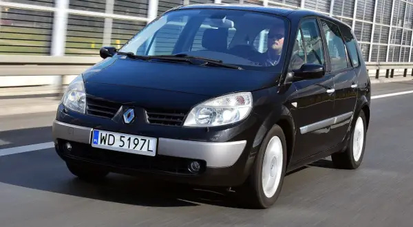 Czarny Renault Scenic 2 1.6 16v na drodze. Kierowca w okularach przeciwsłonecznych.