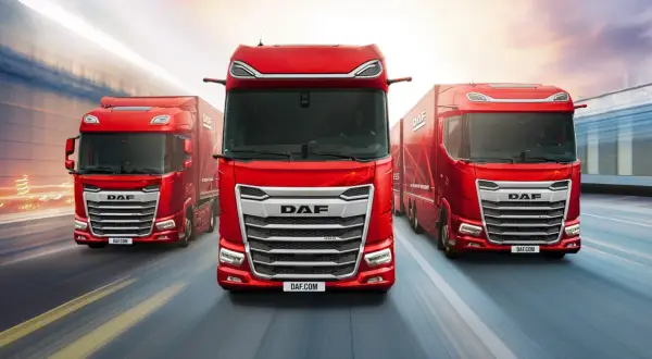 Trois camions DAF rouges sur une route floue. L'intérieur du DAF XF est visible, avec un conducteur au volant.