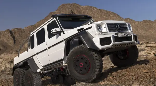 Biały Mercedes G63 AMG 6x6 z sześcioma kołami na skalistym pustynnym terenie.
