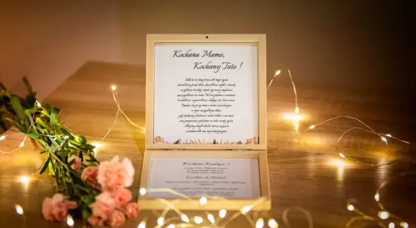Drewniana szkatułka z listem od dzieci, zawierająca błogosławieństwo rodziców na ślub, ozdobiona kwiatami i światełkami.