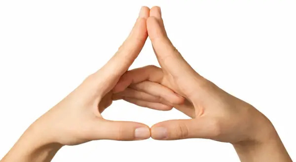 Manos formando un triángulo, un gesto de mudras de protección para invocar seguridad y equilibrio.