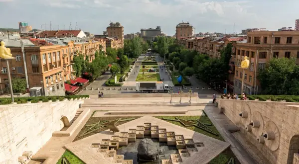 Widok na kaskady i aleję w Erywaniu. Monumentalne schody prowadzą do zielonej alei z rzeźbami i budynkami w tle.