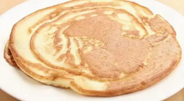 Ein goldbrauner Pfannkuchen ohne Ei auf einem weißen Teller, perfekt für ein leichtes Frühstück.