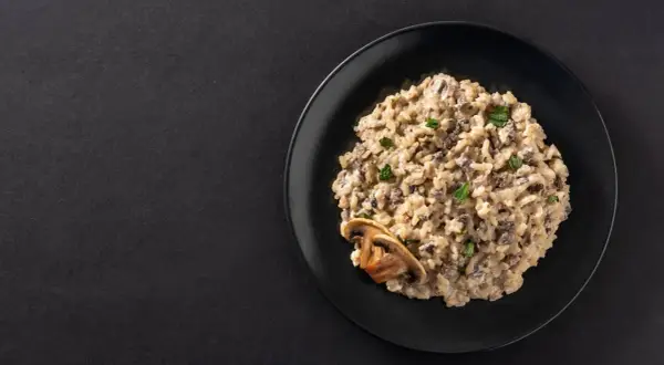 Un crémeux risotto aux champignons, garni de persil frais et d'une tranche de champignon. Un délice végétarien.