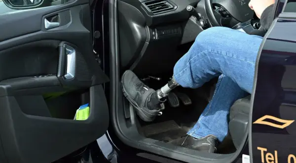 Autofahren mit Orthese links: Person mit Prothese am linken Bein bedient Automatik-Auto.