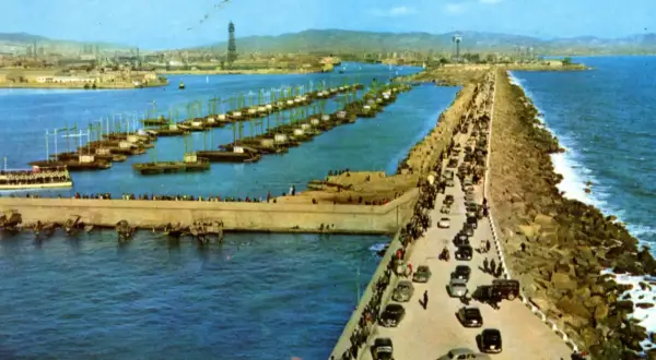 El rompeolas de Burela, con barcos alineados y coches circulando, protege la costa de las olas.