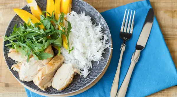 Idealne danie, co jeść po treningu: grillowany kurczak, ryż, mango i rukola na talerzu.