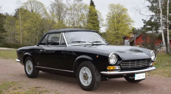 Svart Fiat 124 Spider till salu, en klassisk cabriolet redo för sommarens äventyr.