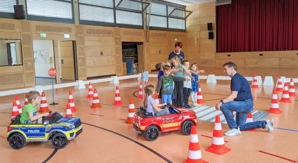 Kinder lernen spielerisch Verkehrsregeln bei der Verkehrserziehung im Kindergarten. Kleine Autos und Pylonen simulieren eine Straße.