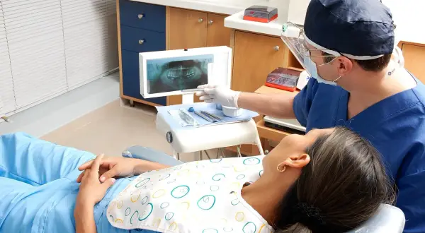 Dentysta omawia z pacjentką zdjęcie RTG, szukając rozwiązań co zamiast leczenia kanałowego.