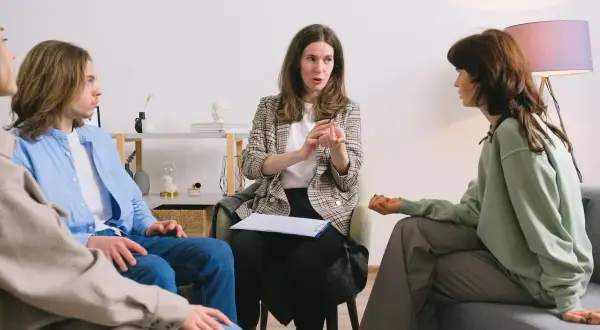 Grupa osób na sesji terapeutycznej z terapeutką uzależnień.