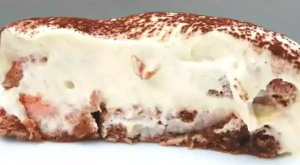 Tranche de tiramisu crémeux, parsemé de cacao, avec des morceaux de biscuit rose. Un délice !